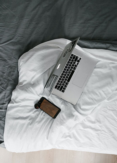 Laptop und Smartphone auf einem Bett im AVES Savognin – Arbeiten und Entspannen im Zimmer