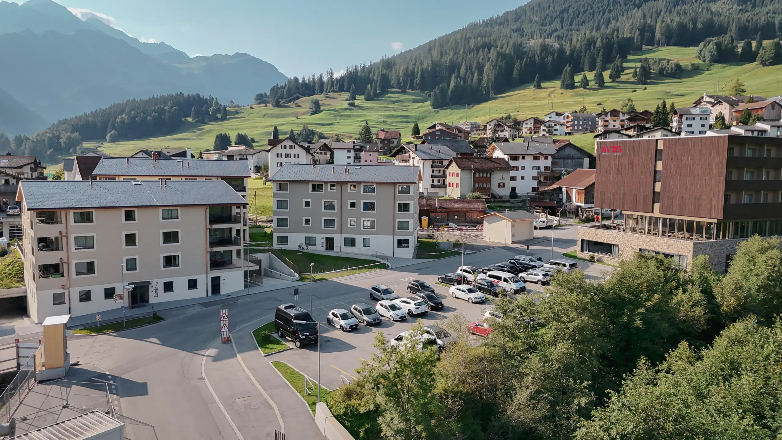 Luftaufnahme von Savognin mit dem AVES Hotel und umliegendem Dorf in der alpinen Sommerlandschaft