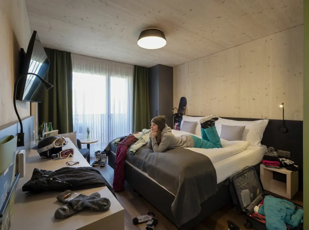 Doppelzimmer im AVES Savognin mit gemütlichem Bett, Balkon und Platz für Outdoor-Ausrüstung
