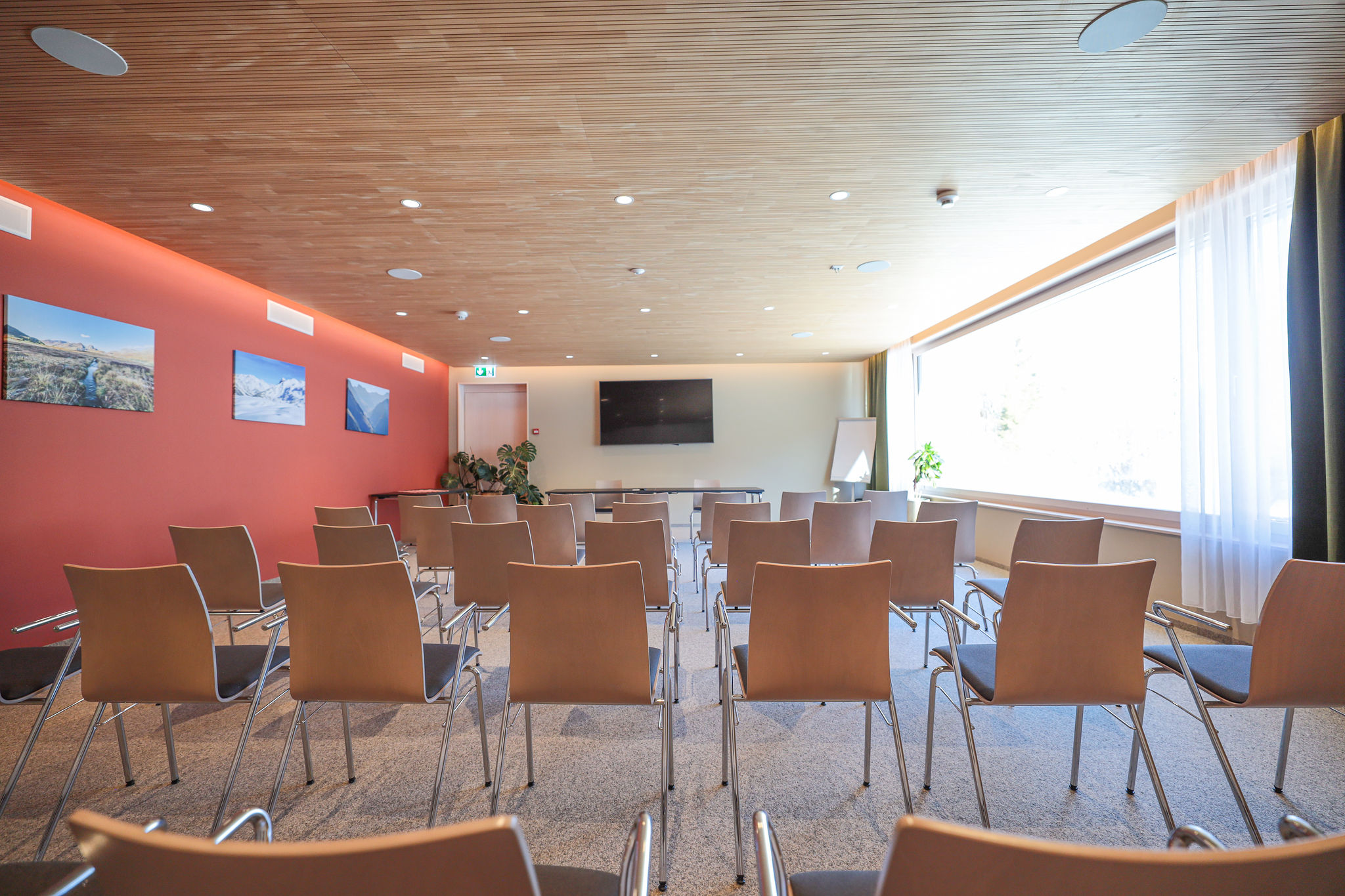 Seminarraum Meeting 1 im AVES Savognin in Theaterbestuhlung mit Blick auf Bildschirm und Flipchart